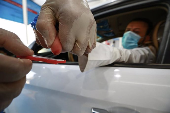 09 August 2020, Iraq, Najaf: An Iraqi medic collects drops of blood from a car driver on a blood collection test kit at a coronavirus (COVID-19) drive-through testing station. Photo: Ameer Al Mohammedaw/dpa