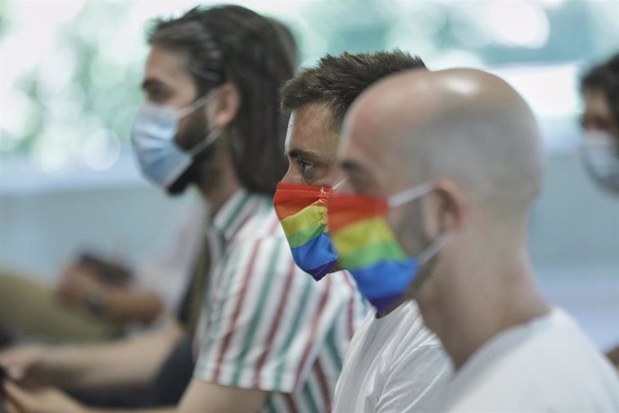 Dos hombres se protegen con mascarillas con la bandera LGTB durante su participación en el acto institucional con motivo del Orgullo 2020, en Madrid (España), a 29 de junio de 2020.