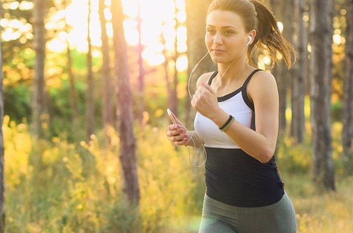 Mujer haciendo deporte mientras escucha música con unos auriculares, running, correr, carrera.