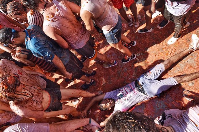 Un joven se tumba en el suelo cubierto con los restos de los tomates arrojados durante la fiesta de la Tomatina de Buñol 2019.