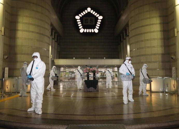 15 May 2020, South Korea, Seoul: Sanitary workers wearing protective suits disinfect the Seoul Central District Court.