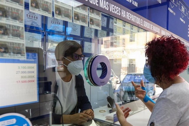 Una lotera atiende a una clienta 