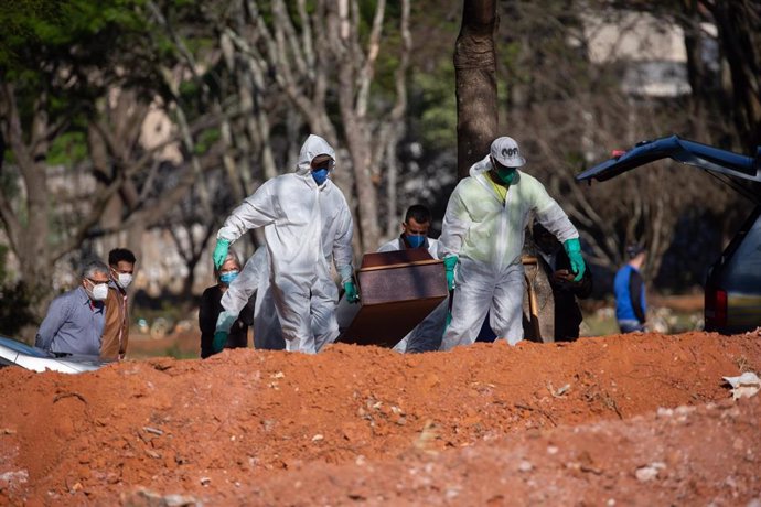 Dos trabajadores del cementerio de Vila Formosa, en Sao Paulo,  trasladan el féretro de una víctima de COVID-19.