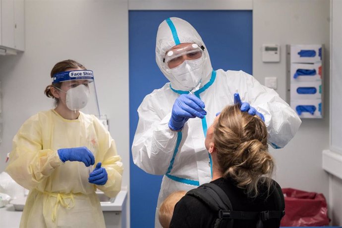 13 August 2020, Baden-Wuerttemberg, Stuttgart: A travel (R) who has been in Switzerland gets tested by medic at a coronavirus testing center set to allow travellers returning from risk areas to take COVID-19 tests at the main railway station in Stuttgart