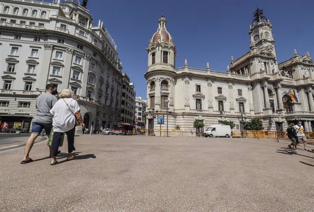 Varias personas pasean por las inmediaciones de las obras de la plaza del Ayuntamiento de Valencia
