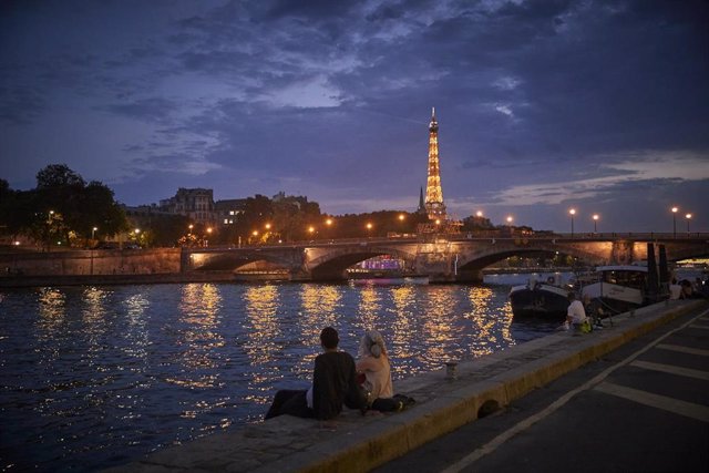 Una pareja sentada junto al río Sena en París