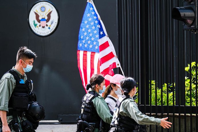 La Policía de Hong Kong lidia con una mujer que portaba una bandera de EEUU frente al consulado estadounidense. 