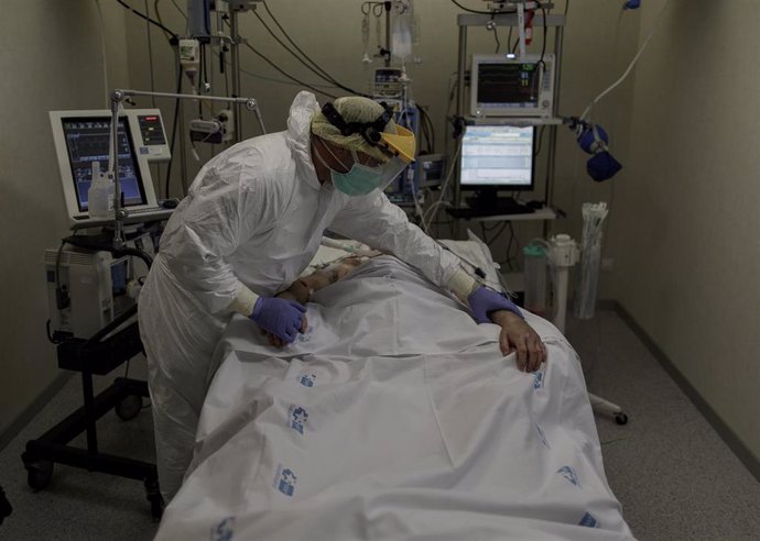 Personal sanitario totalmente protegido atiende a un paciente ingresado en una UCI