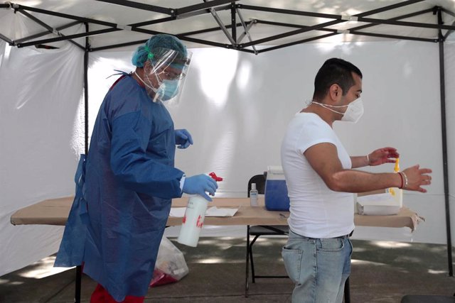 Un profesional sanitario desinfecta a un persona en México. 