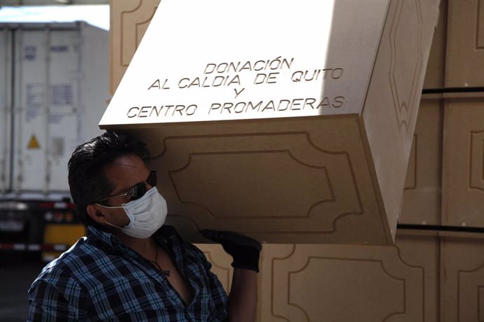 Un hombre carga con uno de los ataudes fabricados de urgencia para hacer frente a la alta demanda que se ha producido en Ecuador en medio de la crisis sanitaria provocada por la COVID-19.
