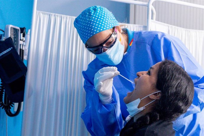Un trabajador sanitario protegido le realiza a una mujer un test PCR en el Centro de Especialidades Carabanchel Alto donde durante la jornada de hoy, el Gobierno regional de la Comunidad de Madrid ha comenzado a realizar pruebas de forma aleatoria a 1.0