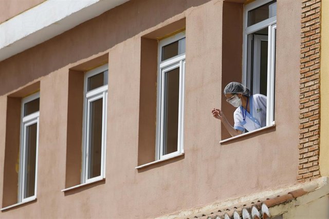 Una trabajadora se asoma a una ventana de  el centro de mayores Cáxar De La Vega, en Cájar (Granada), afectado en marzo por un brote