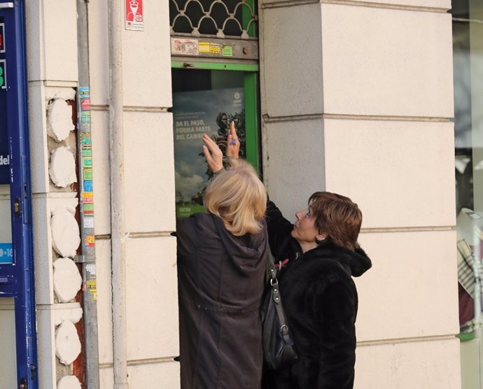 Dues dones tanquen la persiana del seu negoci