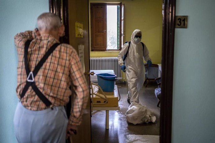 Un anciano contempla en una residencia la actuación del personal sanitario.