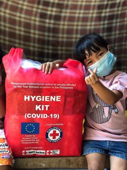 Una niña junto a un kit de higiene de Cruz Roja. 