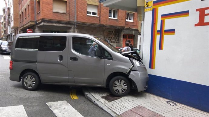 Furgoneta empotrada contra una tienda de pinturas, resultado del choque con otro vehículo, en Gijón