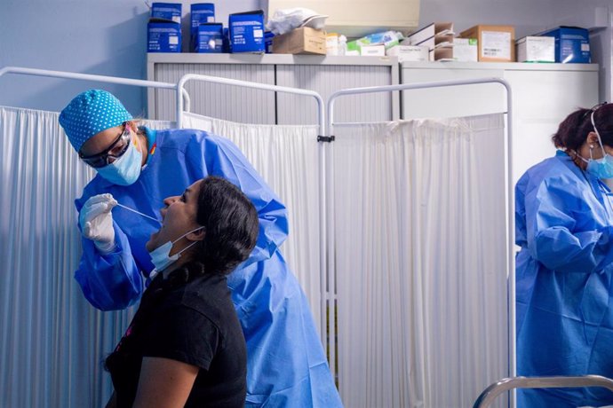 Un trabajador sanitario protegido le realiza a una mujer un test PCR en el Centro de Especialidades Carabanchel Alto.