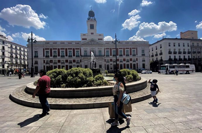 Varias personas pasean junto a una de las fuentes de la Puerta del Sol de la capital.