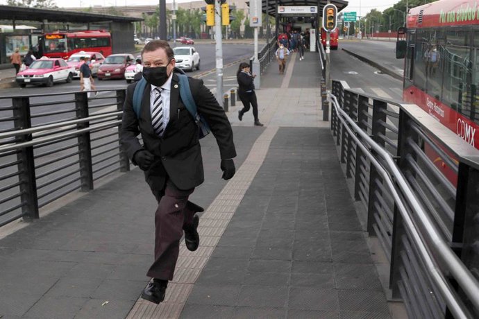 Un hombre con mascarilla se apresura por las calles de Ciudad de  México para no perder el autobus.