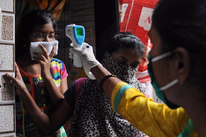 Una trabajadora sanitaria toma la temperatura a una mujer durante una campaña puerta a puerta de test de COVID-19 en Bombay