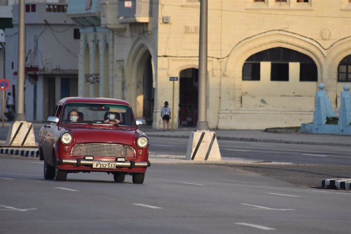Personas con mascarillas en un coche por las calles de La Habana