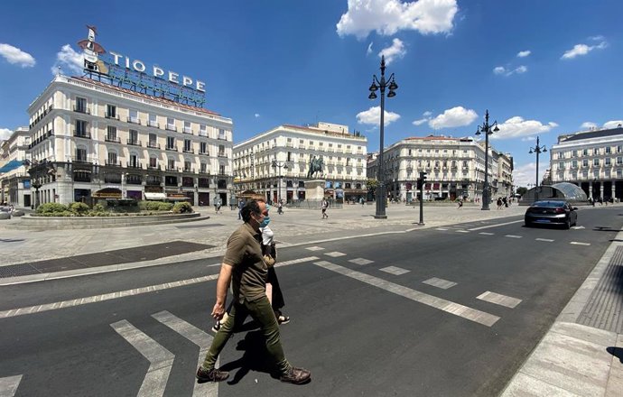 Dos personas cruzan la calle en la Puerta del Sol de la capital.