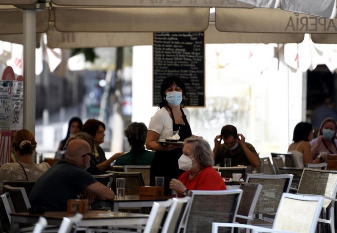 Una camarera con mascarilla atiende a los clientes en una terraza en Madrid. 