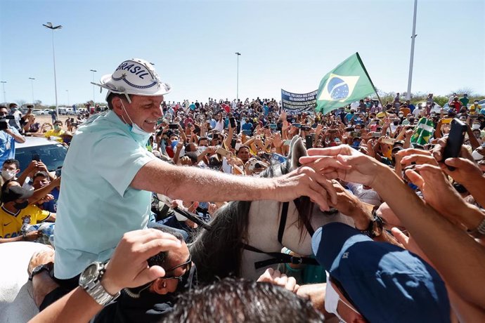 El presidente de Brasil, Jair Bolsonaro, a lomos de un caballo mientras es agasajado y vitoreado por sus múltiples incondicionales, que desafiando las leyes de distanciamiento por la pandemia se amontona para tocar la mano de su líder.