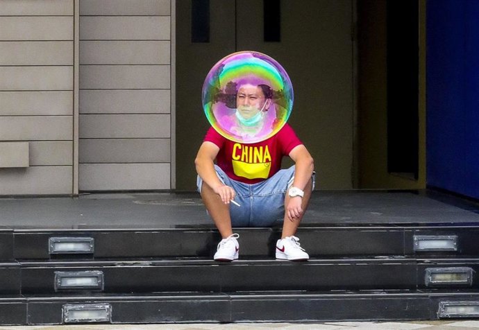 Una pompa de jabón flota hasta colocarse frente a un ciudadano chino que había salido a echarse un cigarrillo.