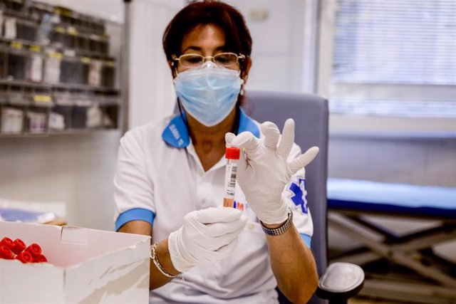 Una trabajadora sanitaria protegida sostiene una de las probetas utilizadas para la realización de PCR.
