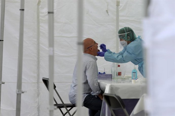 Una sanitria li realitza un frotis bucal a un veí d'Ordizia en una de les carpes installades al parc Barrina per l'Ajuntament d'Ordizia per realitzar test davant el possible brot de COVID-19