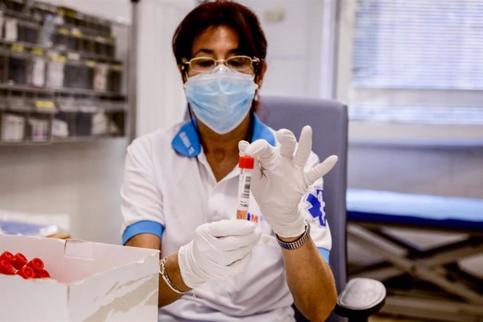 Una trabajadora sanitaria protegida sostiene una de las probetas utilizadas para la realización de PCR