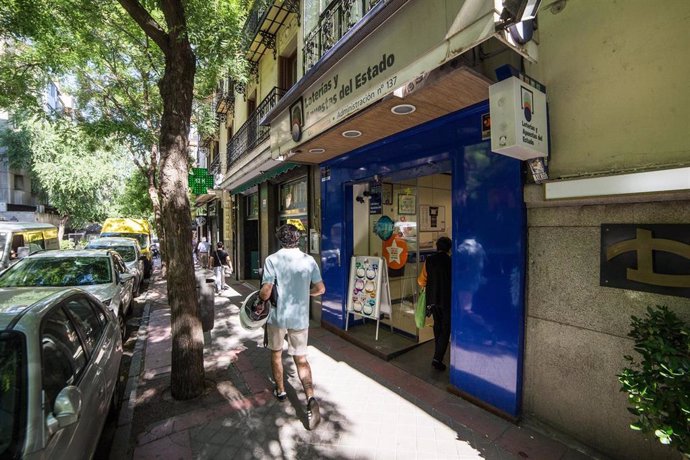 Un hombre pasa al lado de una administración de lotería abierta en Madrid.
