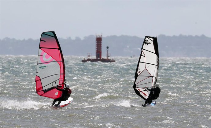 27 June 2020, England, Hampshire: People windsurf over the water in the sea off Calshot beach. Photo: Andrew Matthews/PA Wire/dpa