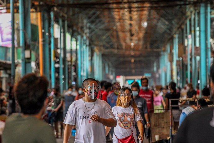 Personas con mascarillas en un mercado de Manila