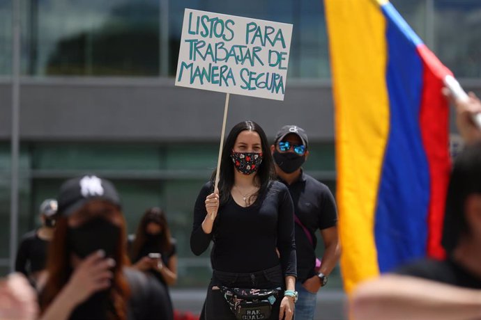 Una mujer manifestándose en Colombia con mascarilla por el coronavirus. 