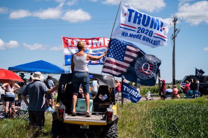 Una mujer sostine una bandera de QAnon durante un mitin de Trump en Minnesota