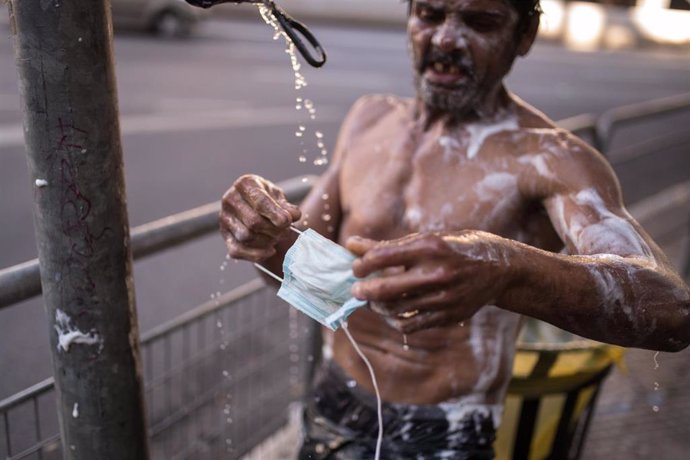 Una persona en situación de calle lava su mascarilla en Sao Paulo, Brasil
