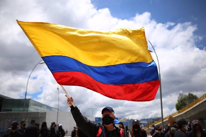 Imagen de un hombre con mascarilla con una bandera de Colombia en Bogotá. 
