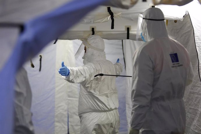 Trabajadores de proteccion civil se desinfectan contra el coronavirus en una carpa instalada en el hospital del PTS de Granada.