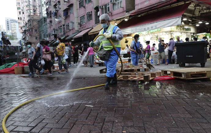 Un trabajador de los servicios de limpieza de Hong Kong limpiando las calles de un mercado local al aire libre