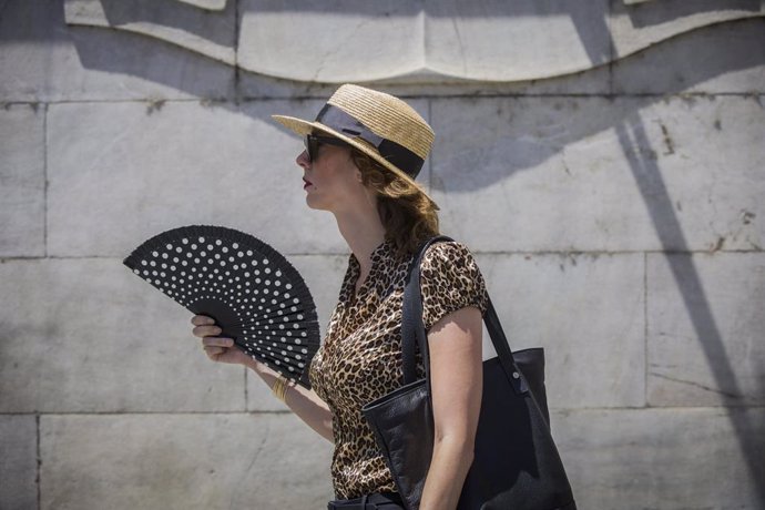 Una mujer se abanica mientras camina por Sevilla