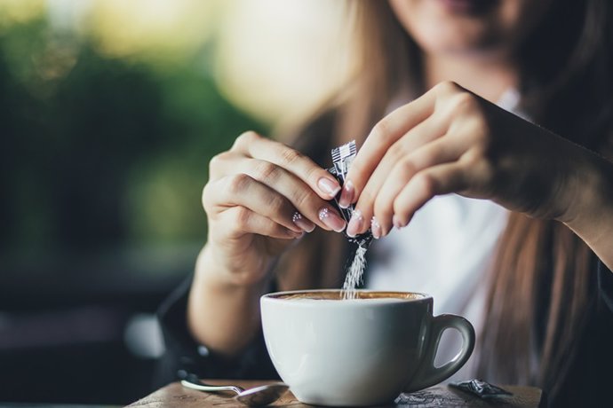 Mujer pone edulcorante en el café