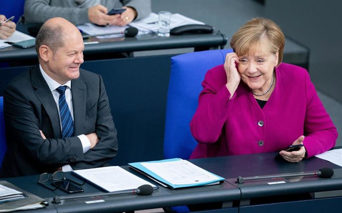 La canciller alemana, Angela Merkel, y el ministro de Finanzas, Olaf Scholz, sonríen durante una sesion del Bundestag en 2019