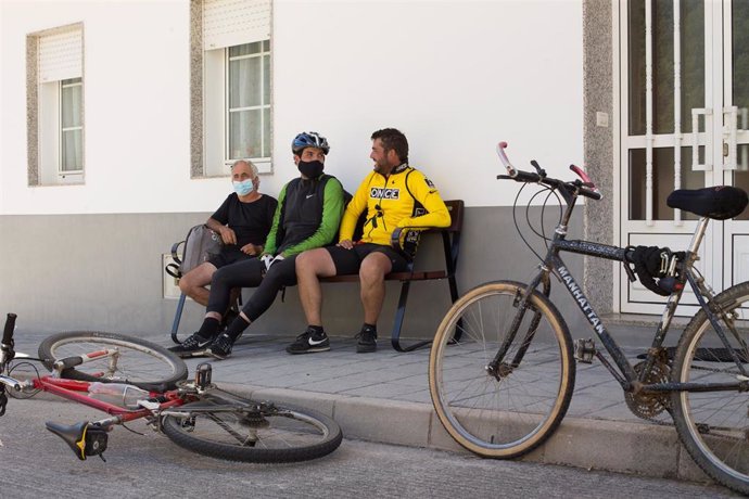 Los hermanos Primi (d) y Mario (c) y su tío Pedro (i), descansan junto a sus bicicletas en un banco de la localidad de Triacastela, fin de su etapa diaria, mientras los peregrinos retornan al Camino francés de la Ruta Jacobea casi un mes después del fin