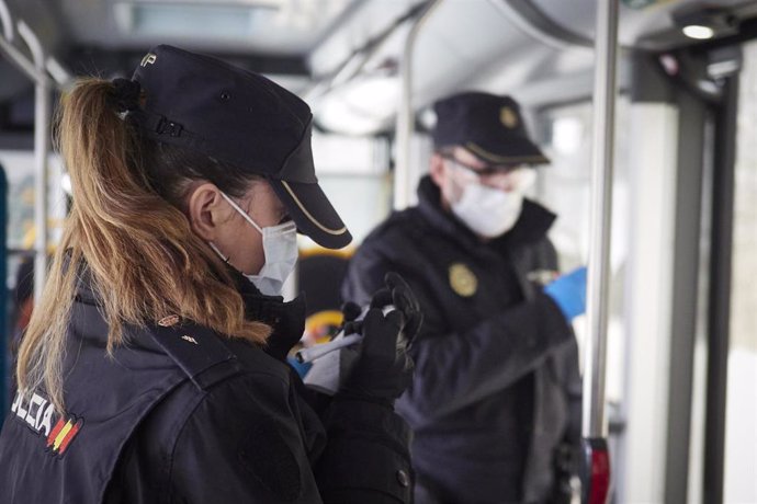 Dos agentes de la Policía Nacional protegidos con mascarillas en un autobús urbano en Pamplona.