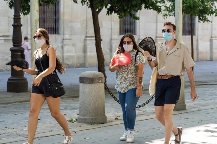 Tres jóvenes pasean con mascarillas por Sevilla