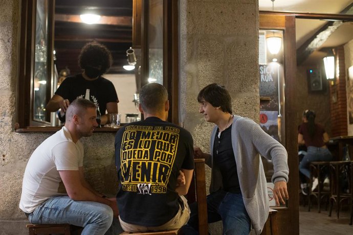 Tres jóvenes a la puerta de un bar durante la noche el mismo día en que el Ministerio de Sanidad ha decretado el cierre de ocio nocturno