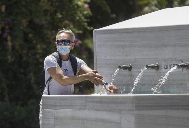 Un hombre se refresca en una fuente