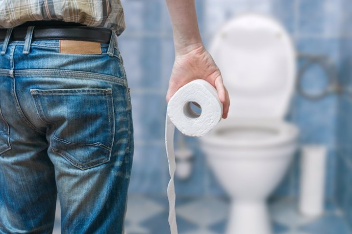 Man suffers from diarrhea holds toilet paper roll    Hombre que sufre de diarrea sostiene un rollo de papel higiénico